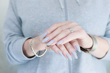 woman hands with long nails light gray blue manicure