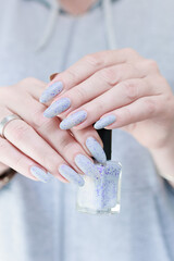 woman hands with long nails light gray blue manicure