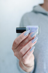 Female hand with long nails and a white gray and purple manicure