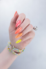 Woman hand with long nails and multi-colored manicure, red, orange and yellow nail polish 