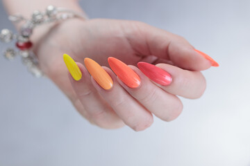 Woman hand with long nails and multi-colored manicure, red, orange and yellow nail polish 