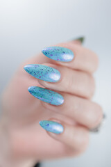 Woman's beautiful hand with long nails and light blue manicure