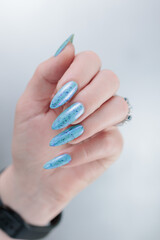 Woman's beautiful hand with long nails and light blue manicure