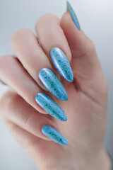 Woman's beautiful hand with long nails and light blue manicure