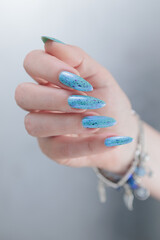 Woman's beautiful hand with long nails and light blue manicure