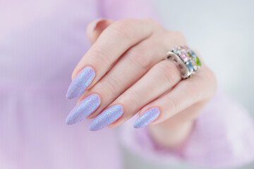 Woman hands with long nails manicure and light blue lilac pink nail polish