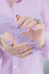 Woman hand with long nails manicure and light blue and pink nail polish
