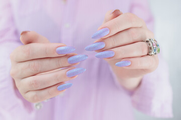 Woman hand with long nails manicure and light pink lilac nail polish