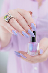 Woman hand with long nails manicure and light pink lilac nail polish