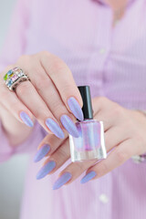 Woman hand with long nails manicure and light blue and pink nail polish