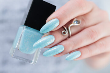 Woman's beautiful hand with long nails and light baby blue manicure	