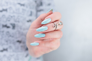 Woman's beautiful hand with long nails and light blue manicure