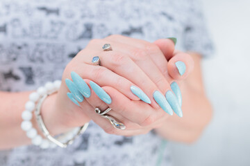 Woman's beautiful hand with long nails and light blue manicure