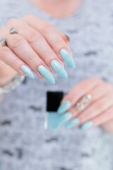 Woman's beautiful hand with long nails and light baby blue manicure