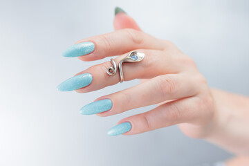 Woman's beautiful hand with long nails and light blue manicure