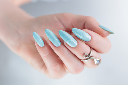 Woman's beautiful hand with long nails and light blue manicure