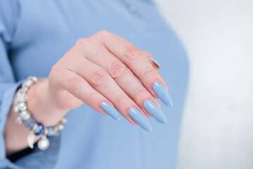 Woman's beautiful hand with long nails and light baby blue manicure