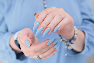 Woman's beautiful hand with long nails and light blue manicure