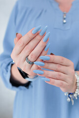 Woman's beautiful hand with long nails and light baby blue manicure