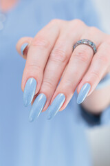 Woman's beautiful hand with long nails and light baby blue manicure