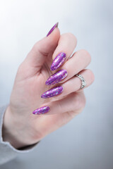 Female hand with long nails and purple plum manicure