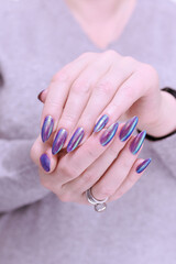 beautiful female hand with long nails, purple and blue manicure 