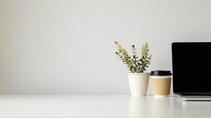 Minimalist office desk setup with potted plant, coffee cup, and laptop against a clean white background. Concept of simplicity and productivity