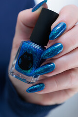 Woman's beautiful hand with long nails and bright blue green manicure