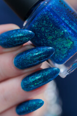 Woman's beautiful hand with long nails and blue and green manicure	