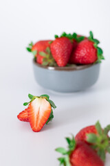 Fresh strawberries in ceramic bowl on white background