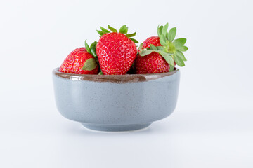 Fresh strawberries in ceramic bowl on white background