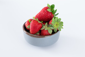 Fresh strawberries in ceramic bowl on white background