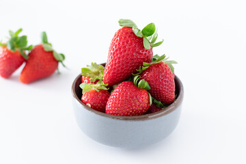 Fresh strawberries in ceramic bowl on white background