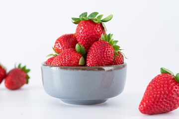 Fresh strawberries in ceramic bowl on white background
