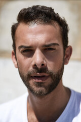 Obraz premium Man, portrait and face with beard outdoor in tshirt as confidence, cool and trendy person in summer. Male model, calm and relax by wall with facial hair for fashion, sexy and aesthetic with pride