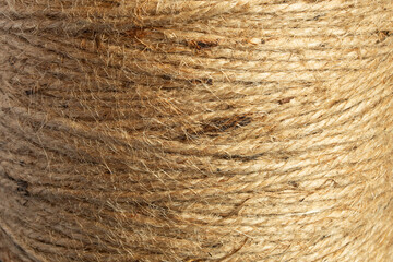 Close-up image of a natural jute twine spool, showcasing the rough, fibrous texture. The organic quality and intricate weave reveal the intertwined strands and fibers, highlighting the rope’s strength