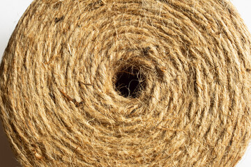 Close-up image of a natural jute twine roll viewed from the top showcasing the central hole, displaying its intricate, fibrous texture captures the detailed pattern and organic quality of the rope.
