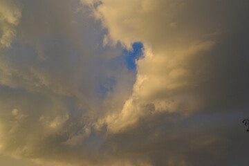 Yellow-blue gray clouds in the evening summer sky. Cumulus clouds.