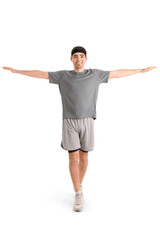 Sporty young man balancing on white background