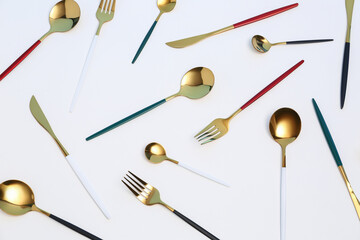 Golden set of cutlery with colorful handles on white background