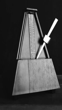 Vertical shot of metronome pendulum is shown at different positions. Helpful for timing, rhythm, and tempo in music practice