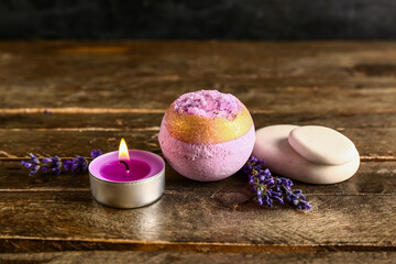 Bath bomb, spa stones, burning candle and lavender flowers on wooden table