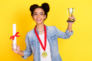 Portrait of nice young girl gold medal diploma trophy wear denim shirt isolated on yellow color...