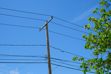 power lines on old wooden pole on a blue sky background in America