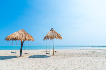 Beautiful swings under Nipa palm umbrella and beach with white sand of the sea on the beach blue sky with clouds on a hot sunny day background ,travel summer holiday Thailand