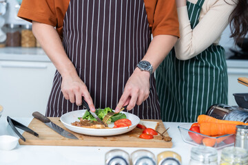close up hand loving young asian of having fun standing a cheerful preparing food and enjoy cook steak cooking and vegetables, meat, bread while standing on a kitchen Condo life or home
