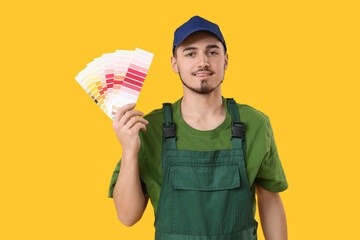 Young painter with color palettes on yellow background