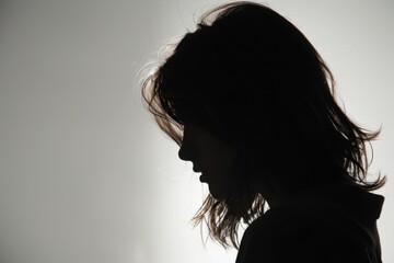Fototapeta premium A silhouette of an adult woman with shoulder-length hair, seen from the side on a white background She is wearing casual and appears to be looking down Generative AI