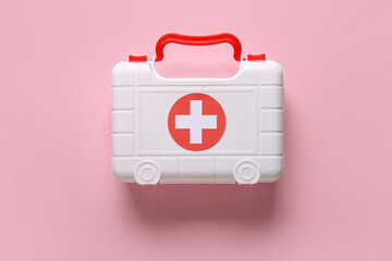 Toy first aid kit on pink background. Top view