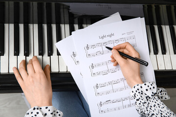 Woman playing piano and writing notes, closeup